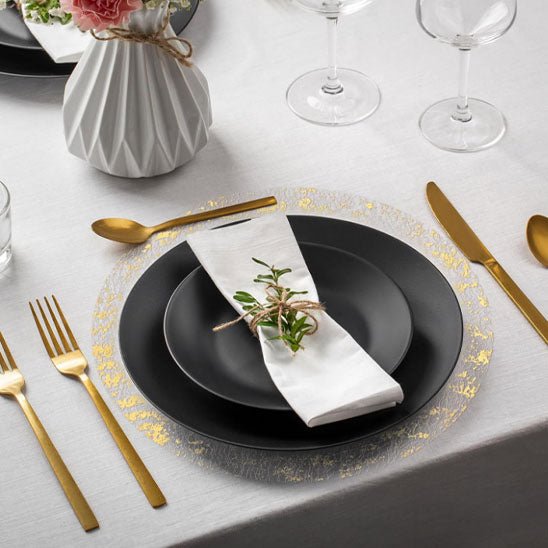 set de table rond assiette noire serviette blanche couverts dores